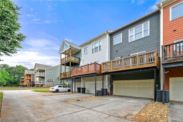 back of property with a garage, central air condition unit, concrete driveway, and a balcony