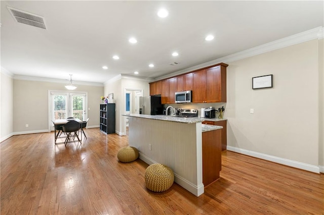 kitchen featuring a kitchen island with sink, stainless steel appliances, baseboards, visible vents, and ornamental molding