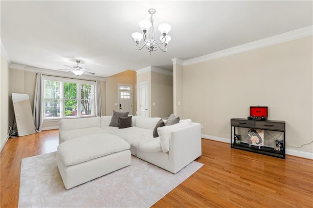 living room featuring crown molding, baseboards, light wood-style floors, and ceiling fan with notable chandelier