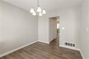 4406 Idlewood Ln, Tucker, GA 30084 - unfurnished dining area with a chandelier, baseboards, and wood finished floors