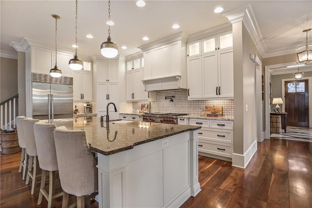 kitchen featuring white cabinets, ornamental molding, dark wood-style flooring, stainless steel gas stovetop, and a sink