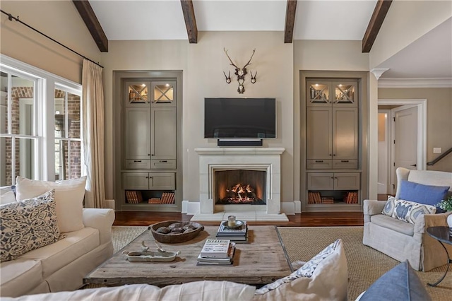 living area with a warm lit fireplace, beamed ceiling, and wood finished floors