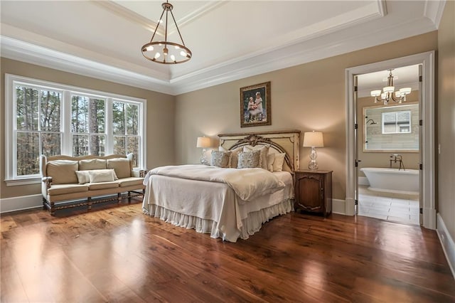 bedroom with baseboards, ornamental molding, wood finished floors, ensuite bathroom, and a tray ceiling