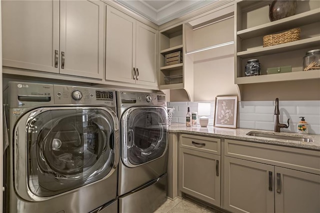 clothes washing area featuring light tile patterned flooring, separate washer and dryer, a sink, cabinet space, and crown molding