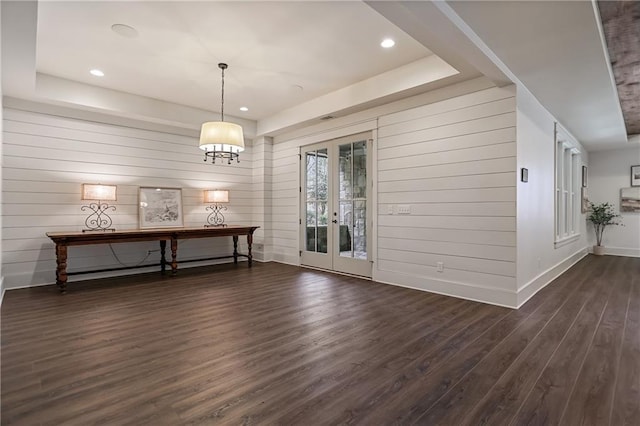 unfurnished dining area featuring french doors, recessed lighting, a raised ceiling, dark wood-type flooring, and baseboards