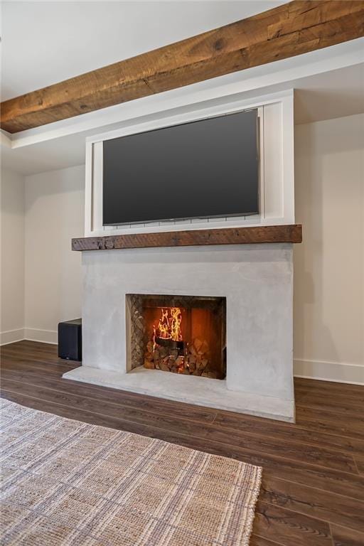 room details featuring a lit fireplace, baseboards, and wood finished floors