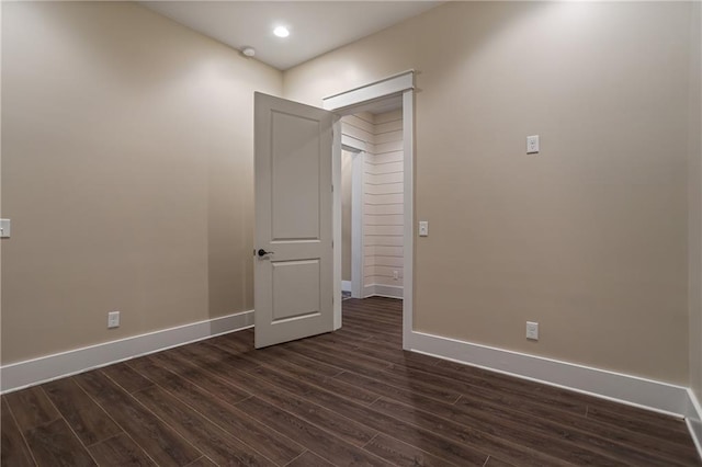 spare room featuring dark wood-type flooring and baseboards