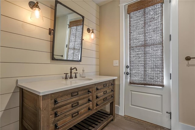 bathroom with wooden walls, wood finished floors, and vanity