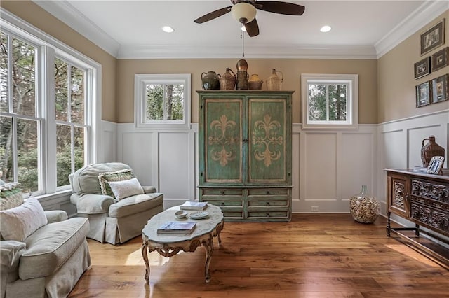 living area featuring a wealth of natural light, crown molding, and wood finished floors