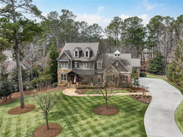 view of front facade with driveway, stone siding, and a front lawn