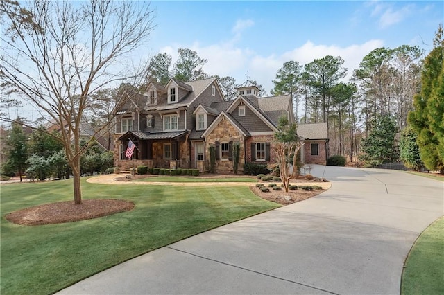 view of front of house featuring stone siding, driveway, a front lawn, and a standing seam roof