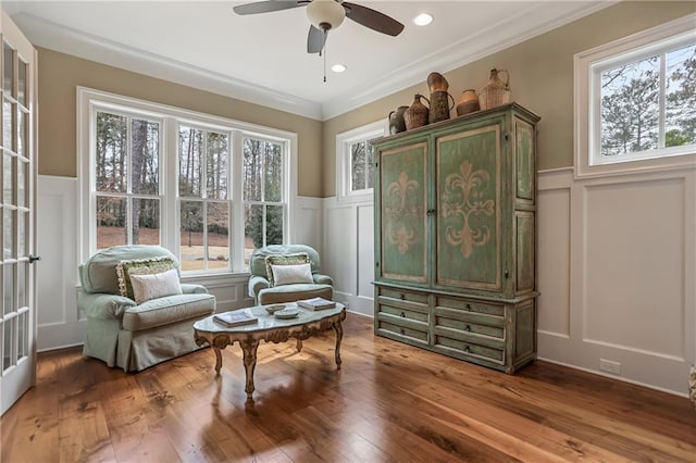 living area featuring a wainscoted wall, crown molding, recessed lighting, a decorative wall, and wood finished floors