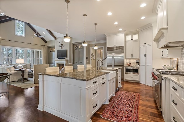 kitchen with lofted ceiling, stainless steel stove, a ceiling fan, open floor plan, and an island with sink