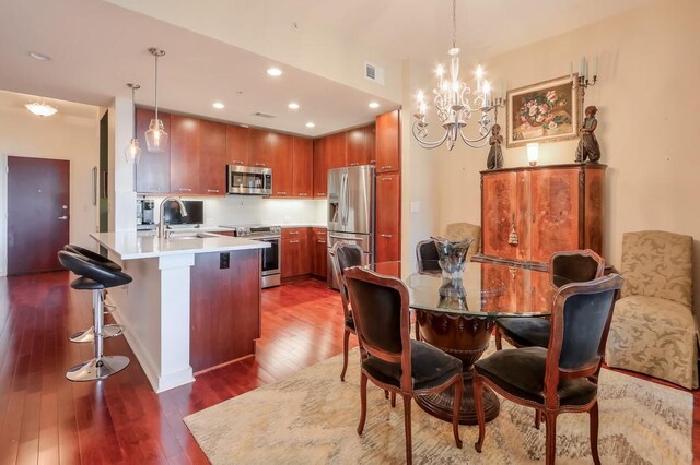 dining space with dark hardwood / wood-style flooring, a notable chandelier, and sink