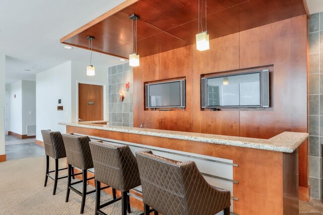 bar with hanging light fixtures and light stone counters