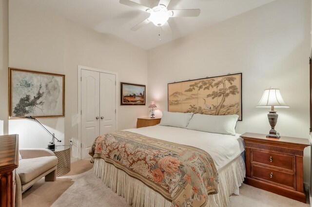 bedroom featuring light carpet, ceiling fan, and a closet