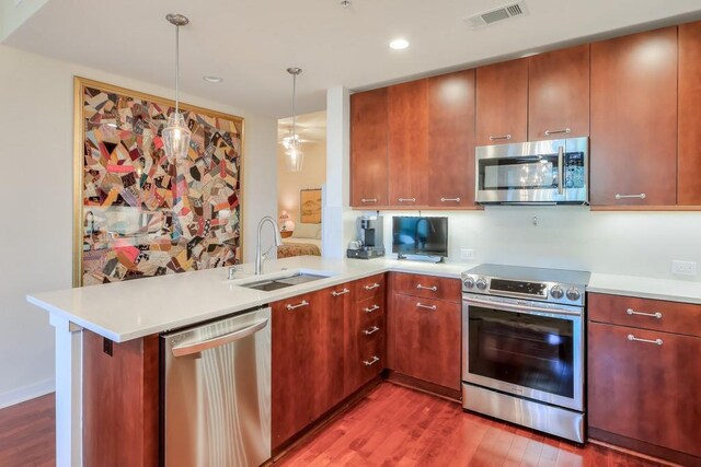 kitchen featuring appliances with stainless steel finishes, hardwood / wood-style flooring, kitchen peninsula, and sink