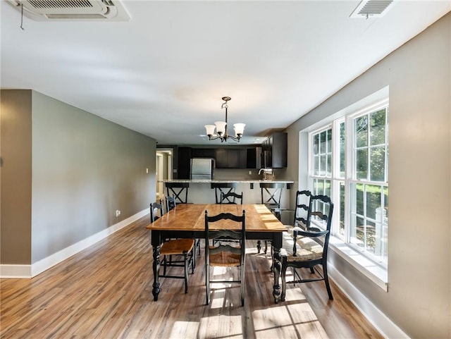 dining room featuring plenty of natural light, a notable chandelier, light wood-type flooring, and sink