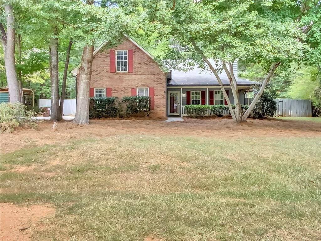 view of front of house featuring a front yard, brick siding, and fence