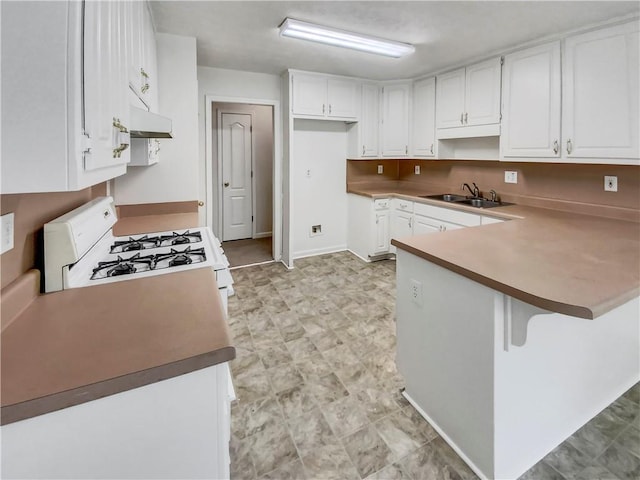 kitchen with under cabinet range hood, white range with gas stovetop, a peninsula, a sink, and white cabinetry