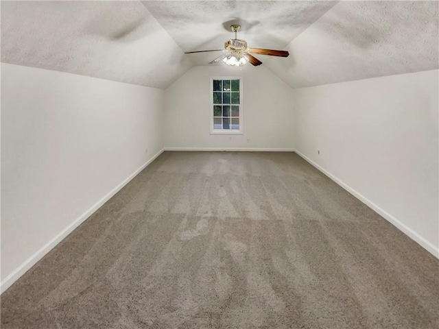 additional living space with baseboards, ceiling fan, vaulted ceiling, a textured ceiling, and carpet floors