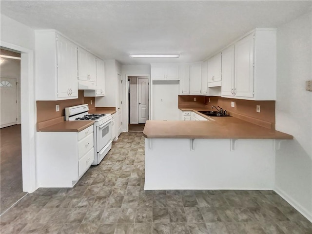 kitchen featuring white cabinetry, white range with gas cooktop, a peninsula, under cabinet range hood, and a kitchen breakfast bar