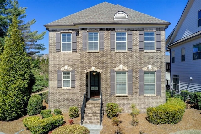 view of front of house with brick siding and roof with shingles