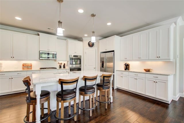 kitchen with a kitchen breakfast bar, a sink, dark wood-style floors, stainless steel appliances, and white cabinetry