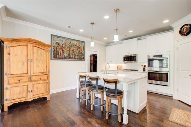 kitchen featuring visible vents, ornamental molding, a breakfast bar area, a sink, and appliances with stainless steel finishes