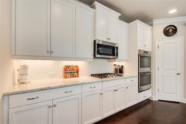 kitchen featuring decorative backsplash, dark wood-style flooring, appliances with stainless steel finishes, light stone counters, and white cabinets