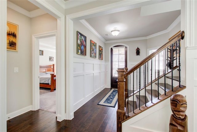 entryway featuring arched walkways, dark wood finished floors, ornamental molding, and a wainscoted wall