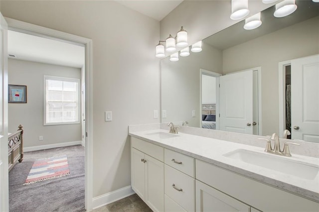 full bath with a sink, baseboards, ensuite bathroom, and double vanity