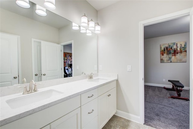 bathroom with baseboards, a sink, double vanity, and a spacious closet