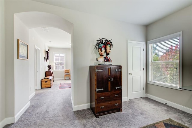 hallway with carpet floors, arched walkways, and baseboards
