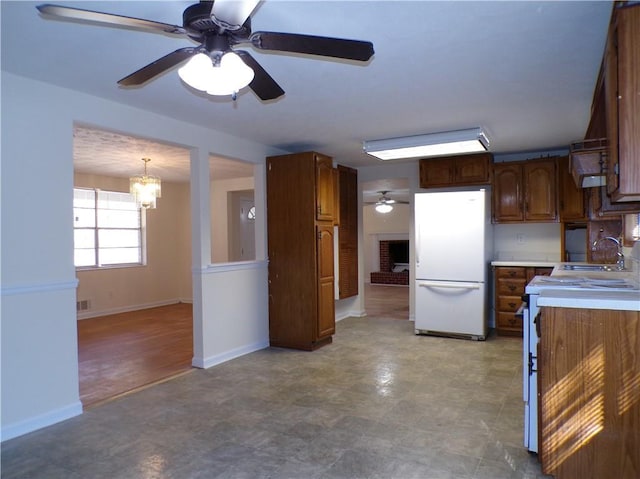 kitchen featuring pendant lighting, white appliances, ceiling fan with notable chandelier, and sink