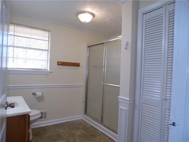 bathroom with vanity, toilet, a shower with door, crown molding, and a textured ceiling