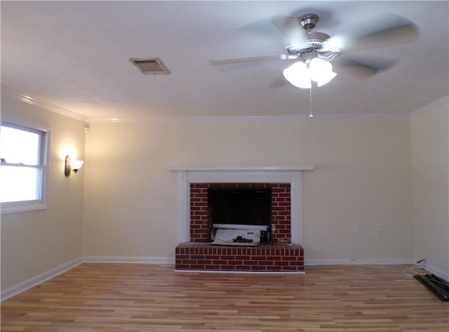 living room with a brick fireplace, crown molding, ceiling fan, and light wood-type flooring