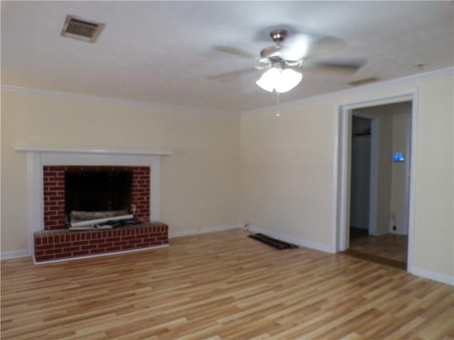 unfurnished living room with ornamental molding, a brick fireplace, and light wood-type flooring