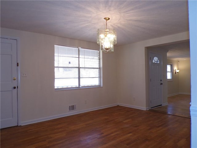 foyer with dark hardwood / wood-style flooring, a notable chandelier, and plenty of natural light