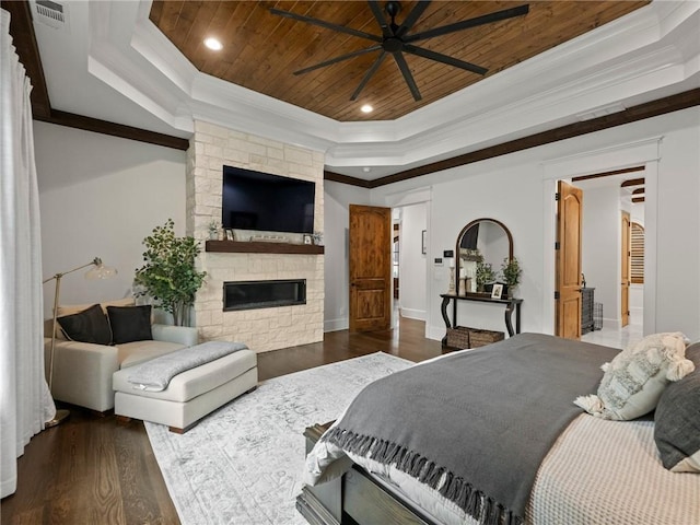 bedroom with visible vents, wood finished floors, a stone fireplace, a raised ceiling, and wood ceiling