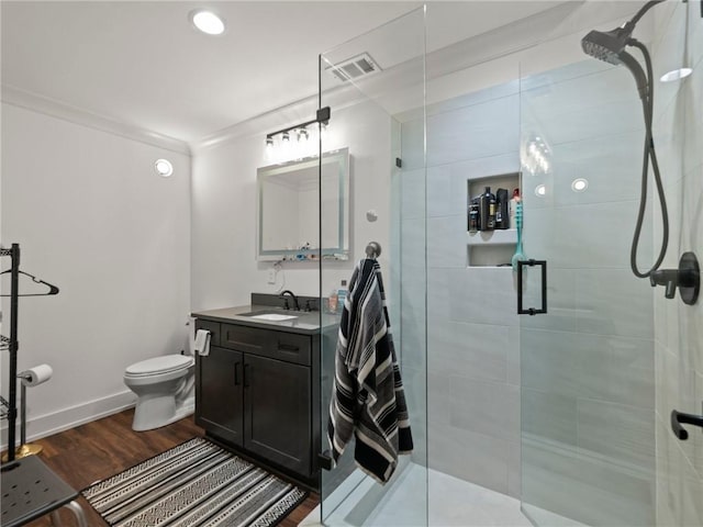 bathroom with a shower stall, baseboards, toilet, wood finished floors, and vanity