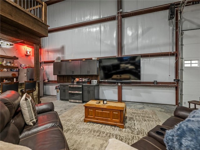 living area with a garage, concrete floors, and a towering ceiling