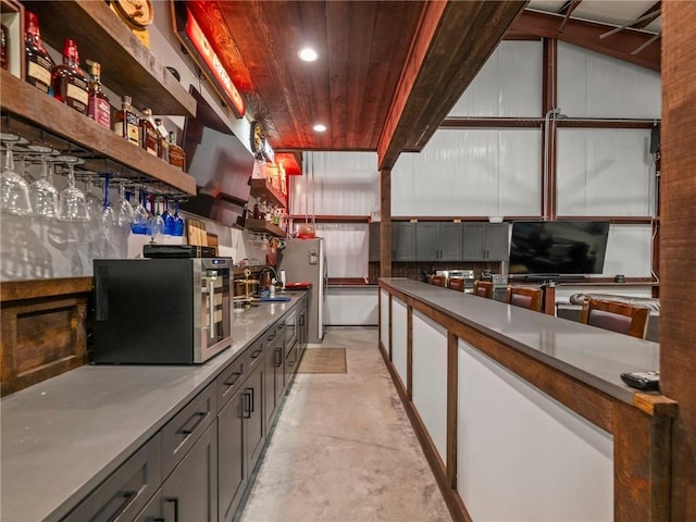 bar with a sink, stainless steel appliances, concrete floors, indoor bar, and wood ceiling