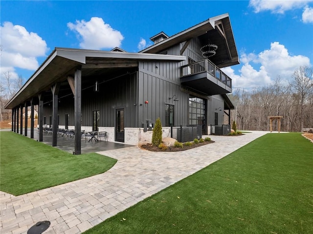 exterior space featuring a yard, a balcony, board and batten siding, and a patio area