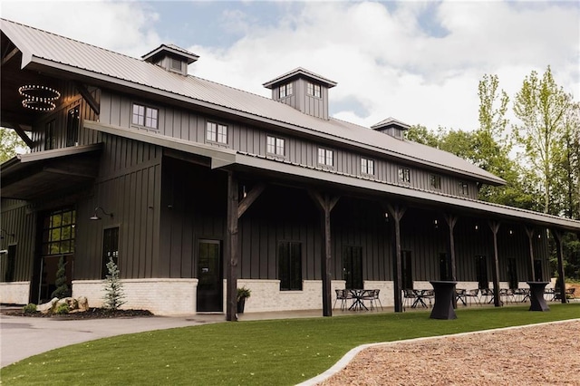 exterior space featuring a front lawn, brick siding, board and batten siding, and metal roof