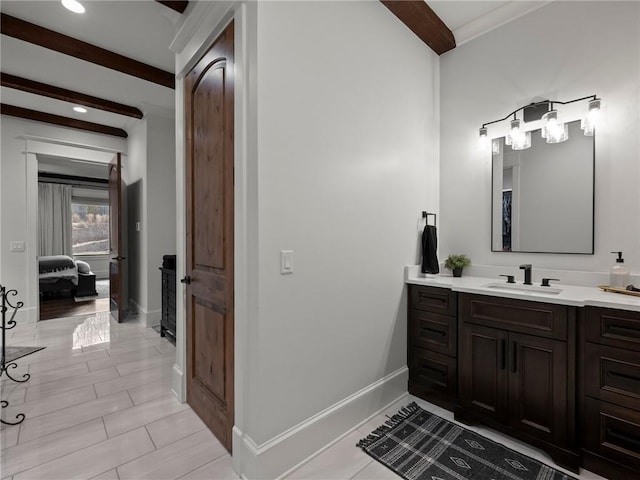 bathroom featuring beamed ceiling, baseboards, and vanity