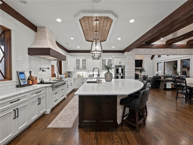 kitchen with custom exhaust hood, beam ceiling, dark wood-style floors, and a sink