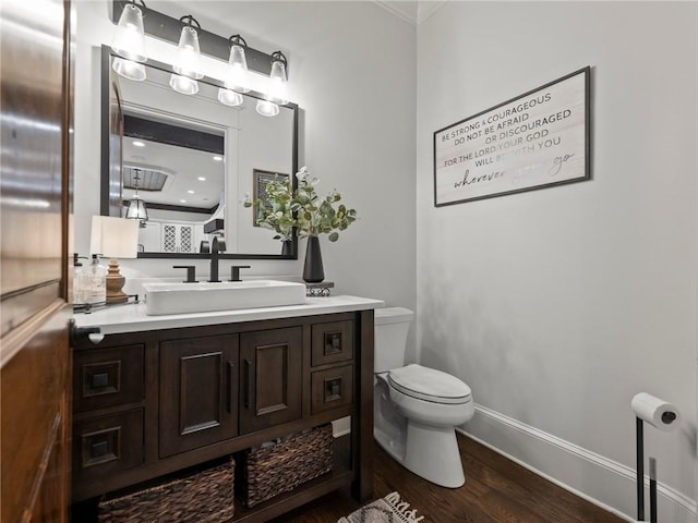 bathroom with toilet, vanity, baseboards, and wood finished floors