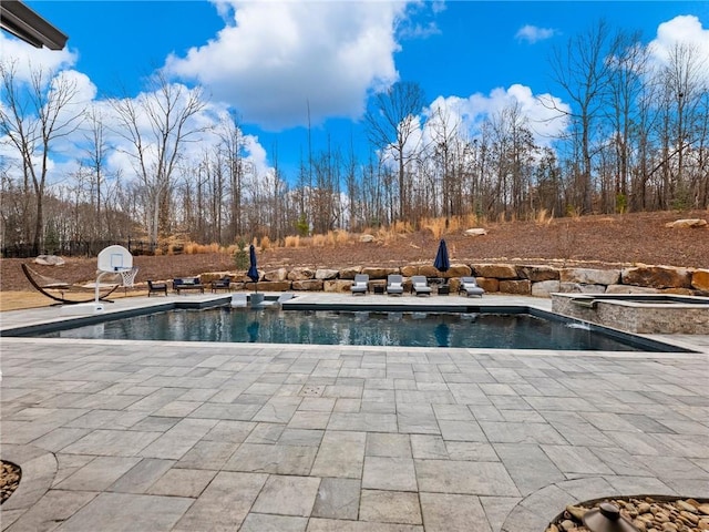 outdoor pool with a patio area and an in ground hot tub