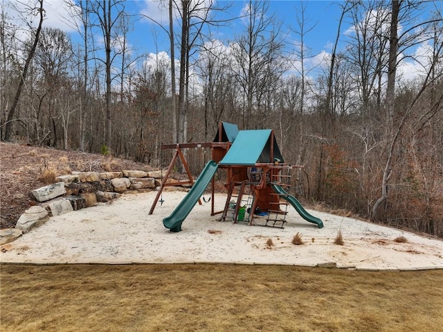 view of jungle gym with a forest view